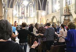 Women hold hands during the Our Father in a packed St. John the Evangelist Church for Mass during the Indiana Catholic Women&rsquo;s Conference in Indianapolis. (Photo by Victoria Arthur)