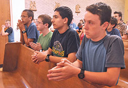 Kneeling in prayer during a Mass that was a part of Bishop Brut&eacute; Days at Bishop Simon Brut&eacute; College Seminary in Indianapolis in June 2016 are John Paul Malinoski, left, Patrick Barron, Leo Ocampo&mdash;all members of Our Lady of the Most Holy Rosary Parish in Indianapolis&mdash;and Isaac Williams, a member of St. John the Apostle Parish in Bloomington. (File photo by Sean Gallagher)