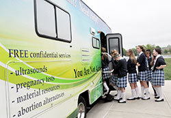 Middle school students of SS. Francis and Clare of Assisi School in Greenwood step onto the Great Lakes Gabriel Project&rsquo;s mobile ultrasound RV unit, which lists its services on the side. (Photo by Natalie Hoefer)