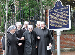 Little Sisters of the Poor Sisters Amy, left, Janet, Gloria, Marthe, Cecilia and Mother Mary Vincent pose on May 20 with a state historical marker that was unveiled on that day at 520 E. Vermont St. in Indianapolis, where the order&rsquo;s first home for the elderly poor in Indianapolis was located from 1873-1967. (Photo by Natalie Hoefer)