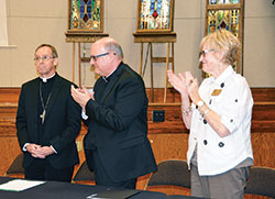 Msgr. William F. Stumpf, archdiocesan administrator, center, and archdiocesan chancellor Annette &ldquo;Mickey&rdquo; Lentz applaud Archbishop-designate Charles C. Thompson after his press conference in the Archbishop Edward T. O&rsquo;Meara Catholic Center in Indianapolis on June 13. (Photo by Natalie Hoefer)