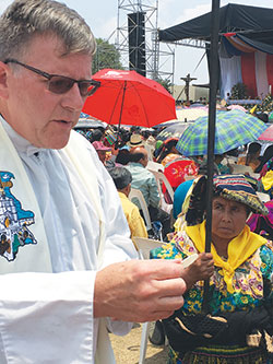 Father Michael O&rsquo;Mara, pastor of St. Gabriel the Archangel Parish in Indianapolis, distributes Communion during the April 27 Mass celebrating the 50th anniversary of the Quiche diocese in Guatemala.
