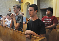 Jacob Sitzman, left, James Mobley, Isaac Williams and Josiah Guerra kneel in prayer during a June 23 Mass during Bishop&nbsp;Brut&eacute; Days at Bishop Simon Brut&eacute; College Seminary in Indianapolis. Jacob is a member of Nativity of Our Lord Jesus Christ Parish in Indianapolis. James and Isaac are members of St. John the Apostle Parish in Bloomington. Josiah is a&nbsp;member of Holy Trinity Parish in Edinburgh. (Photo by Sean Gallagher)