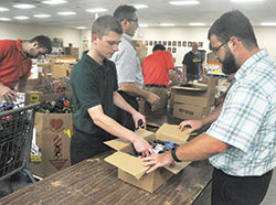 Seminarians Samuel Rosko, left, and Michael Dedek box drinks on Aug. 8 at the Society of St. Vincent de Paul&rsquo;s Pratt-Quigley Client Choice Food Pantry in Indianapolis. The morning of volunteer service at the pantry took place during the annual archdiocesan seminarian convocation. (Photo by Sean Gallagher)