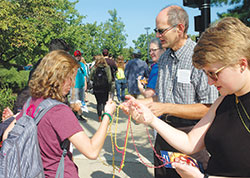 Deacon Russell Woodard, parish life coordinator of Holy Trinity Parish in Edinburgh, and Kelley Snoddy (in blue shirt) of St. Bartholomew Parish in Columbus pass out rosaries and prayer cards to a group of young people as they share their Catholic faith near a farmer&rsquo;s market in Columbus on Aug. 26. (Photo by John Shaughnessy)