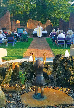 A dedication Mass was celebrated on Sept. 20 marking the opening of Holy Trinity Heritage Park in New Albany. Shown giving a homily during the outdoor liturgy is Father Wilfred &ldquo;Sonny&rdquo; Day, pastor of St. John the Baptist Parish in Starlight. The park is located next to St. Elizabeth Catholic Charities&rsquo; social services office building, which was once the church rectory. (Submitted photo)