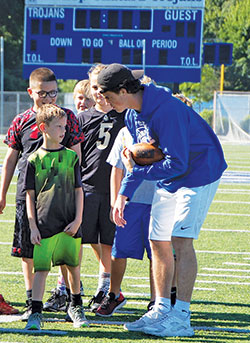 Sports camps are among the ways that Catholic high schools in the archdiocese try to make a continuing connection with students from nearby parish schools. Here, Josh Coons, a student-athlete of Bishop Chatard High School in Indianapolis, shares a tip during a football camp for third- to eighth&shy;graders at the school in the summer of 2017. (Submitted photo)