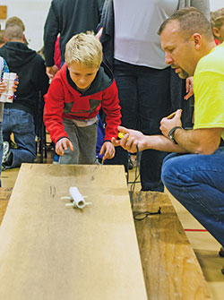Maddox Novotney launches his improvised &ldquo;car&rdquo; while Matt Maddox marks its speed with a timer during the second annual Family STEM Night on Nov. 16, 2017, at St. Barnabas School in Indianapolis. (Submitted photo)