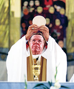Then-Archbishop Daniel M. Buechlein elevates the Eucharist during a Sept. 16, 2000, Mass in the RCA&nbsp;Dome in Indianapolis to celebrate the jubilee year. More than 30,000 Catholics participated in the Mass. (File photo)