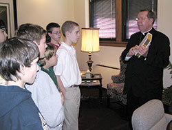 Archbishop Daniel M. Buechlein, right, shows a special edition of the Catechism of the Catholic Church to a group of students from St. Pius X School in Indianapolis during a visit on Jan. 27, 2009, to his office in the Archbishop Edward T. O&rsquo;Meara Catholic Center in Indianapolis. Archbishop Buechlein played a significant role in the renewal of catechesis in the U.S. while serving as chairman of the U.S.&nbsp;bishops&rsquo; Ad Hoc Committee on the Use of the Catechism of the Catholic Church. (File photo by Sean Gallagher)