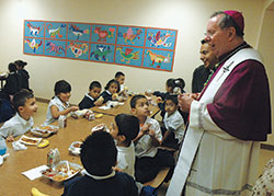 Archbishop Daniel M. Buechlein laughs while chatting with members of St. Philip Neri School&rsquo;s kindergarten class on Oct. 20, 2009. He visited the school that day to bless it after major renovations had been completed. (File photo by Sean Gallagher)