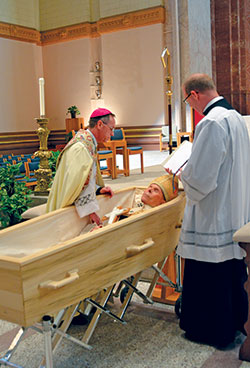 Archbishop Charles C. Thompson, left, prays over the body of Archbishop Emeritus Daniel M. Buechlein during the Rite of Reception on Jan. 30 in SS. Peter and Paul Cathedral in Indianapolis. Father Patrick Beidelman, executive director of the Secretariat for Worship and Evangelization and rector of the cathedral, assists. During the Rite of Reception, the body of Archbishop Buechlein was prayed over and blessed with holy water, and a cross and breviary were placed in the casket. (Photo by Natalie Hoefer)