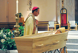 Archbishop Charles C. Thompson spends a quiet moment in prayer by the body of Archbishop&nbsp;Emeritus Daniel M. Buechlein after a Solemn Evening Prayer liturgy on Jan. 30 at SS. Peter and Paul Cathedral in Indianapolis. (Photo by Sean Gallagher)