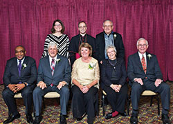 An archdiocesan celebration of Catholic education on Feb. 22 honored three individuals and a parish group whose Catholic values mark their lives. Sitting, from left, are honorees Ody Oruche, Dan and Jan Megel, keynote speaker St. Joseph Sister Carol Cimino, and Gary Ahlrichs, representing the men&rsquo;s group of Immaculate Heart of Mary Parish in Indianapolis. Standing from left, are archdiocesan superintendent of schools Gina Fleming, Archbishop Charles C. Thompson, and Father Jeffrey Godecker, who helped found the men&rsquo;s group of Immaculate Heart of Mary Parish in 2001. (Photo by Rob Banayote)