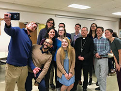 Indiana University students crowd in for a photograph with Archbishop Charles C. Thompson at St. Paul Catholic Center in Bloomington on Feb. 25. This was the archbishop&rsquo;s first visit to the parish as leader of the archdiocese. (Photo by Katie Rutter)