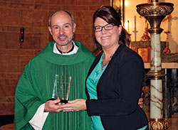 During Catholic Schools Week in January, Gina Fleming, superintendent of Catholic schools in the archdiocese, presents an award to Father Christopher Wadelton, pastor of St. Philip Neri Parish in Indianapolis, honoring him as an archdiocesan nominee for the national &ldquo;Lead, Learn, Proclaim&rdquo; Award from the National Catholic Educational Association (NCEA). Since then, Father Wadelton has been chosen for the national honor which recognizes &ldquo;excellence and distinguished service in Catholic school education.&rdquo; He will receive the award on April 3 at the NCEA convention in Cincinnati. (Submitted photo)