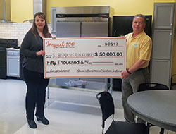 Development director Dawn Bennett and agency director Mark Casper, both of St. Elizabeth Catholic Charities in New Albany, hold a symbolic check representing $50,000 that the organization won last September through Impact 100 of Southern Indiana&rsquo;s inaugural annual grant. The money was used to build a multiple-station kitchen to implement a new residential culinary training program, and to renovate a shelter kitchen for both training practice and residential use. Bennett and Casper are standing in the renovated kitchen. (Submitted photo)