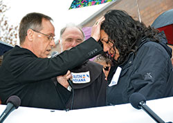 Archbishop Charles C. Thompson prays over Erika Fierro outside of the Department of Homeland Security office in Indianapolis on April 24 prior to her meeting asking for a &lsquo;credible fear interview.&rsquo; Also&nbsp;pictured is Franciscan Father Larry Janezic. (Photo by Natalie Hoefer)