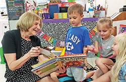 For 44 years, Terry Horton has served as a teacher and an administrator in Catholic schools in the New Albany Deanery. Here, she shares a book and a smile with pre-kindergarten students Liam McGuire,&nbsp;left, Mia Wilkinson and Raegan Schoen. (Submitted photo)