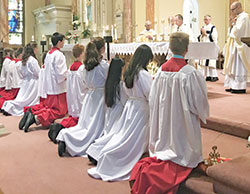 Altar servers kneel in prayer while Archbishop Charles C. Thompson prays the eucharistic prayer during a June 3 Mass at St. Joseph Church in Shelbyville to celebrate the 150th anniversary of the Batesville Deanery faith community&rsquo;s founding. (Submitted photo by Amy Johnson)