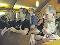 Tessa Guillaume, left, kneels in prayer during the June 24 anniversary Mass to celebrate the 50th&nbsp;anniversary of the founding of St. Isidore the Farmer Parish in Perry County, with her parents, Stacey and Ty Guillaume, and her sister, Serena&nbsp;Guillaume. (Photo by Sean Gallagher)
