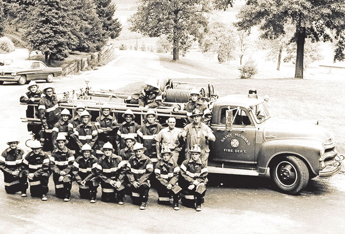 Volunteer firefighters from St. Meinrad, including several Benedictine monks, pose with their truck in this photo which originally appeared in The Criterion on Oct. 14, 1966. At that time, the fire department included two companies, one to serve the town of St. Meinrad, and the other to serve Saint Meinrad Archabbey. Second from the right in the first row is Hubert Werne, captain of the town company, and on the far right in the first row is Benedictine Brother Daniel Linskens, captain of the abbey company. On the far right in the second row is Benedictine Father Kevin Ryan, who was rector of the former Saint Meinrad Seminary High School and served as fire marshal. The volunteer fire department continues to be headquartered today at the eastern foot of the hill on which Saint Meinrad Archabbey and the seminary it operates is located. Benedictine Brother Benjamin Brown, who joined the fire department in 1972, is the only monk firefighter at this time.