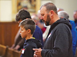 Robbie Falcone, right, and his sons Elijah and Jonah (partially obscured) of St. Elizabeth Ann Seton Parish in Richmond, attend Mass at St. John the Evangelist Church in Indianapolis during the Indiana Catholic Men&rsquo;s Conference on Nov. 10. (Photo by Katie Rutter)