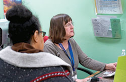 Sally Dreyer, a volunteer through the Retired and Senior Volunteer Program, checks a client in at the St.&nbsp;Vincent de Paul Food Pantry in Indianapolis on Nov. 6. (Still shot from Catholic News Service video by Katie Rutter)