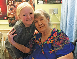 Nathalie Plum, left, a senior at Indiana University and a member of St. Paul Catholic Center, both in Bloomington, embraces Melia Davis, a resident of Golden LivingCenter in Bloomington, on Nov. 16. Plum is a volunteer with Never Alone: Ministry to the Elderly, a program of the campus ministry of St. Paul Catholic Center. (Photo by Natalie Hoefer)