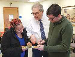 During a visit to the archdiocese&rsquo;s Crisis Office in Indianapolis, Takecia Keys, left, gets help filling out a food selection form from David Bethuram, center, executive director of Catholic Charities in the archdiocese, and Zach Sperka, assistant director of the Crisis Office. (Submitted photo)