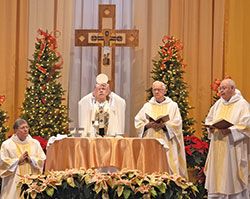 Archbishop Charles C. Thompson elevates the Eucharist during a Mass on Jan. 13 to celebrate the 50th anniversary of the founding of St. Paul Catholic Center in Bloomington. Around the altar are clergy from the parish, from left, Deacon Ron Reimer, Dominican&nbsp;Father Justice Pokrzewinski and Dominican Father John Meany. (Photo by Katie Rutter)