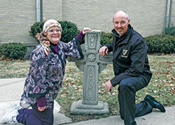 Linda Clodfelter and Father Christopher Wadelton are all smiles as they pose for a photo near a Celtic cross on the grounds of the former Holy Cross Parish in Indianapolis. Both are involved in the 29th annual St. Patrick&rsquo;s Day celebration in the Holy Cross Central School gymnasium on March 10&mdash;a celebration that helps feed the homeless, shut-ins and other people in need throughout the year. (Photo by John Shaughnessy)