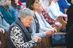 Left, Harla Lyle, a member of St.&nbsp;Susanna Parish in Plainfield, prays during Mass in St. John the Evangelist Church in Indianapolis during the Indiana Catholic Women&rsquo;s Conference on March 23. (Photo by Katie Rutter)