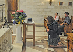 Theresa Inoue, coordinator of evangelization and missionary discipleship at SS. Peter and Paul Cathedral Parish in Indianapolis, kneels in prayer on May 8 before the cremated remains of William&nbsp;&ldquo;Paco&rdquo; Pryor before a funeral for him in the cathedral&rsquo;s Blessed Sacrament Chapel. Pryor had lived as a homeless person for more than 20 years behind the cathedral and died on April 3 in a nursing home in Indianapolis. (Photo by Sean Gallagher)