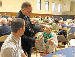 Archbishop Charles C. Thompson meets 9-month-old Miriam Babb and her parents, Rory and Diana Babb, at the third annual Circle of Giving dinner held on May 9 at the Archbishop Edward T. O&rsquo;Meara Catholic Center in Indianapolis. The Babbs, who are members of St. John the Evangelist Parish in Indianapolis, were among those recognized for their generous contributions to the Archdiocese of Indianapolis and its ministries. (Photo by Victoria Arthur)