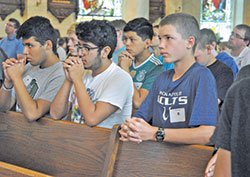 Jose Trinidad, left, Jose Ortiz and Brandon Todd kneel in prayer on June 26 during a Mass at St.&nbsp;Francis Xavier Basilica in Vincennes. The three were among 39 high school participants in Bishop Brut&eacute; Days, an annual archdiocesan vocations camp. Trinidad and Ortiz are members of St. Bartholomew Parish in Columbus. Todd is a member of St. Patrick Parish in Terre Haute. (Photo by Sean Gallagher)