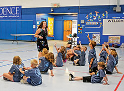 Youths of Holy Family Parish in New Albany raise their hands to answer a question posed by Totus Tuus catechist Jackie Parkes in the parish&rsquo;s school gymnasium on June 19. (Photo by Natalie Hoefer)