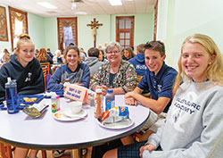 Franciscan Sister Kathleen Branham, center, smiles with her &ldquo;adopted&rdquo; students in the lunchroom at the motherhouse of the Sisters of St. Francis of Oldenburg in Oldenburg on Oct. 9. The sisters invite students from the Oldenburg Academy of the Immaculate Conception to eat lunch together twice a month. The students are, from left, Kate Walke, Emerald Simmonds, Lleyton Knecht and Kate Voegele. (Photo by Katie Rutter)