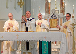 Father Rick Nagel elevates the Eucharist in St. John the Evangelist Church in Indianapolis during a Mass celebrated for those attending the annual Indiana Catholic Men&rsquo;s Conference on Oct. 5. Concelebrants include Father Michael Keucher, left, Father Michael Lightner and Congregation of Marians of the Immaculate Conception Father Donald Calloway. Approximately 375 men attended the conference. (Photo by Mike Krokos)