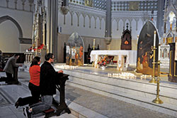 People kneel in prayer on Nov. 2 in St. John the Evangelist Church in Indianapolis before two paintings that the downtown parish commissioned. They portray St. Francis Xavier and St. Theodora Gu&eacute;rin, the archdiocese&rsquo;s two patron saints. Father Rick Nagel, St. John&rsquo;s pastor, blessed the paintings created by parishioner Michael McCarthy during an All Souls Day concert of Gabriel Faure&rsquo;s &ldquo;Requiem.&rdquo; (Photo by Sean Gallagher)