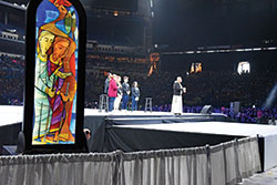 Franciscan Friar of the Renewal Father Agostino Torres and a group of youths lead National Catholic Youth Conference participants in a period of lectio divina (&ldquo;holy reading&rdquo;) prayer on Nov. 22 in Lucas Oil Stadium in Indianapolis. An image depicting part of the story from the Gospel of St. Luke about the disciples on the road to Emmaus created by Benedictine Brother Martin Erspamer sits adjacent to the main stage during the prayer session. (Photo by Sean Gallagher)