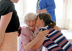 Lesley Bartone, administrative coordinator for the Office of Mission and Ministry at Marian University in Indianapolis, gives a kiss to Franciscan Sister Norma Rocklage on July 15 in Marian&rsquo;s Allison Mansion during a farewell reception for Sister Norma, who retired after nearly 30 years of ministry at the school. She was also at Marian from 1965-74, teaching Latin and Greek and serving as academic dean. (Submitted photo)
