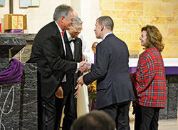 Outgoing Indianapolis Legatus chapter president Jim Huntington, left, shakes hands with newly inducted members Dave and Victoria Temple during Mass at St. Michael the Archangel Church in Indianapolis on Dec. 12, 2019. To Huntington&rsquo;s right is Legatus founder Tom Monaghan. (Photo by Natalie Hoefer)