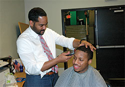 Even in his role as interim president of Providence Cristo Rey High School in Indianapolis, Fred Yeakey finds time to give free haircuts to students, including senior Richard Underwood. Yeakey uses the haircuts as part of his plan of &ldquo;grooming the outer man while guiding the inner man.&rdquo; (Photo by John Shaughnessy)