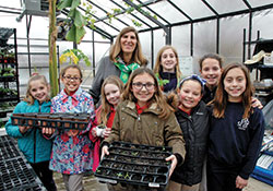 Members of the horticulture club at St. Bartholomew School in Columbus pose for a photo with principal Helen Heckman in the school&rsquo;s greenhouse-outdoor learning lab in early March. (Photo by John Shaughnessy)
