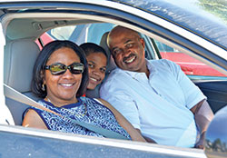 Gretchen, left, Austin and Reggie Horne, members of Holy Angels Parish in Indianapolis, smile in their car after worshiping at an outdoor Mass celebrated by Archbishop Charles C.  Thompson at the parish school&rsquo;s parking lot on June 7. Worshipers remained in their cars during the Mass to observe COVID-19 safety guidelines. (Photo by Natalie Hoefer)