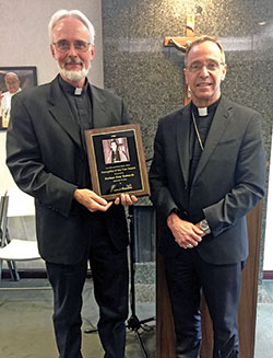 Father Guy Roberts, pastor of St. Joan of Arc Parish in Indianapolis, poses with Archbishop Charles C. Thompson after the archbishop presented him with Catholic Radio Indy&rsquo;s first-ever Archbishop Fulton Sheen Evangelist of the Year award in the organization&rsquo;s Indianapolis office on Sept. 9. (Photo by Natalie Hoefer)