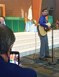 Carlos Ramirez, left, records a video of his son, Carlos Roberto Ramirez of Laredo, Texas, right, as Roberto sings a song during the archdiocesan &ldquo;Morning with Mary&rdquo; event at St. Jude Church in Indianapolis on Oct. 10. (Photo by Natalie Hoefer)