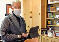 Retired Msgr. Paul Koetter types into a tablet on Oct. 29 in his office at Holy Spirit Parish in Indianapolis, where he previously served as pastor. Amyotrophic lateral sclerosis, commonly known as Lou Gehrig&rsquo;s disease, has taken away his ability to speak. He types what he wants to say, and software on his tablet vocalizes his words in what sounds like his voice. (Photo by Sean Gallagher)