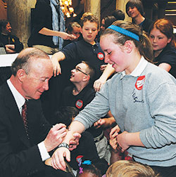 Then-Gov. Mitch Daniels signs Celia Ward&rsquo;s arm following the school choice bill signing ceremony on May 5, 2011. At the time, Celia was a fourth-grade student at Central Catholic School in Indianapolis, one of four schools which now make up the Notre Dame ACE Academies in Indianapolis. (Criterion file photo courtesy of the Governor&rsquo;s Office)